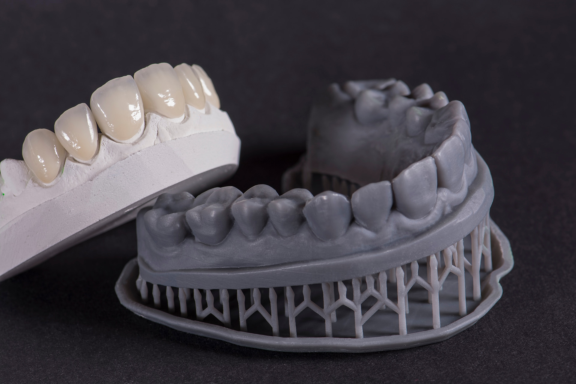 Dentist holding a 3D-printed crown next to a digital scanner